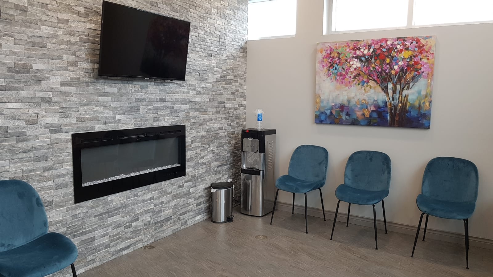 Waiting area with Tv, water dispenser and the chair with painting on the wall