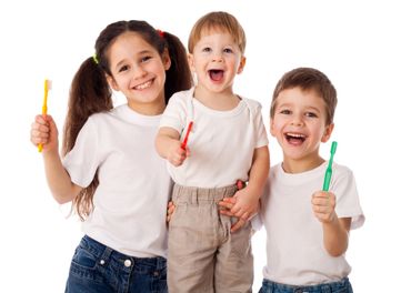 happy kids holding toothbrushes Three happy kids holding toothbrushes